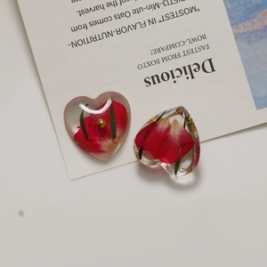 Macro shot of heart-shaped resin earrings with real red dried rose petals inside