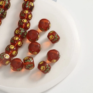 Detailed macro view of 14mm amber translucent resin beads with painted leaf and smiley face