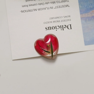 Detailed macro view of heart resin pendant with embedded red dried flower and leaf