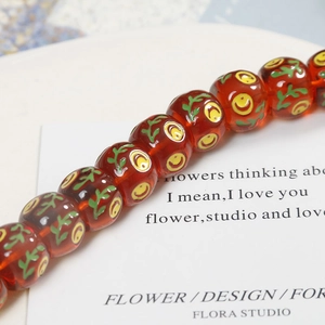 Macro view of 14mm orange resin beads with hand-painted green leaves and yellow patterns