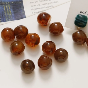 Close-up of amber resin beads with marble pattern and handmade DIY earring on a white desk
