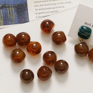 Close-up of amber resin beads with marble texture and elegant green stud earrings