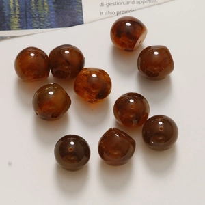 Detail of ten amber-colored resin beads with internal swirl patterns for DIY jewelry