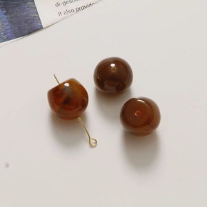 Detailed view of amber-textured resin beads with golden metal pins for DIY jewelry making