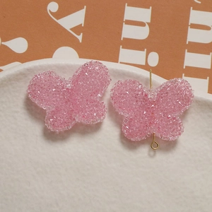 Macro detail of pink resin butterfly jewelry accessory with grainy sugar texture surface