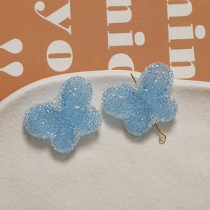 Macro shot of light blue resin butterfly accessories with sugar texture and gold pin