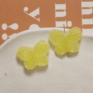 Detailed macro view of yellow butterfly resin charms with a textured sugar glitter finish
