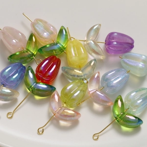 Macro view of iridescent tulip beads and acrylic leaf charms for DIY jewelry making