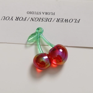 Dettaglio del ciondolo ciliegia rossa traslucida con finitura iridescente per DIY