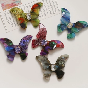 Macro detail of five colorful acetate butterfly charms with central crystal rhinestones