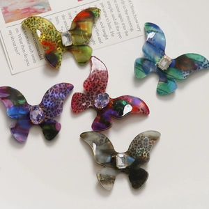 Macro detail of gradient acetate butterfly charms with leopard pattern and inlaid gems