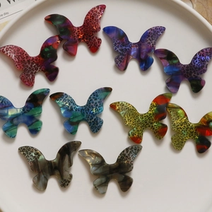 Macro shot of 10 colorful leopard print acetate butterfly pendants in a white tray