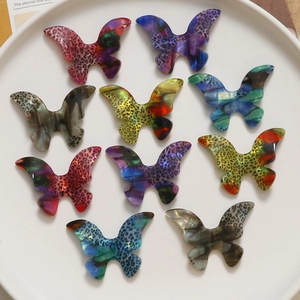 Macro shot of 9 colorful acetate leopard print butterfly pendants in a white tray