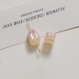 Macro shot of iridescent pink tulip-shaped acrylic beads with gold connector pins