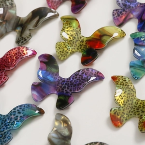Detailed view of assorted leopard print and gradient acetate bird-shaped charms for DIY jewelry