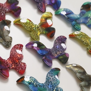 Detailed view of assorted colorful gradient acetate butterfly charms with leopard patterns