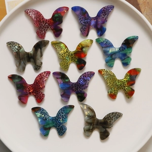 Macro shot of 10 colorful acetate butterfly charms with leopard print in a white tray