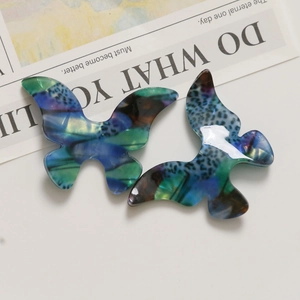 Macro shot of blue and green marble patterned acetate butterfly charm for jewelry making