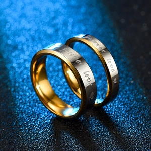 Primer plano de anillos de acero inoxidable con chapado en oro y grabado forever love