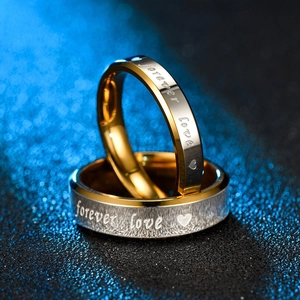 Detalle macro del grabado Forever Love y patrón de corazón en anillos de acero titanio