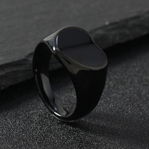 Minimalist black polished stainless steel signet ring on a textured slate background