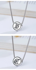 Macro detail of silver gothic letter B and D pendants on stainless steel bead necklaces