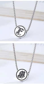 Detail of silver stainless steel round pendant with black gothic letter engraving