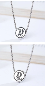 Detailed macro view of silver steel round pendant with engraved floral letter D on box chain