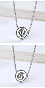 Detail of square box chain and round titanium pendant with engraved gothic letter