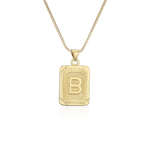 Primer plano de collar dorado de acero con colgante rectangular de letra B y textura de rayos