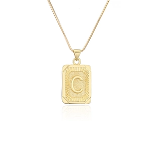 Primer plano de colgante cuadrado dorado con letra C y textura de moneda retro