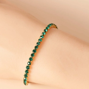 Dettaglio macro di strass verde smeraldo incastonati in un bracciale tennis dorato