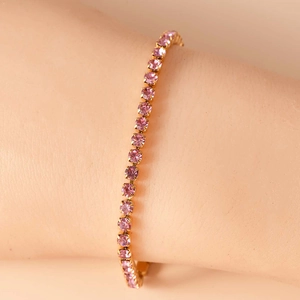 Dettaglio del bracciale tennis con zirconi rosa e base in metallo dorato al polso