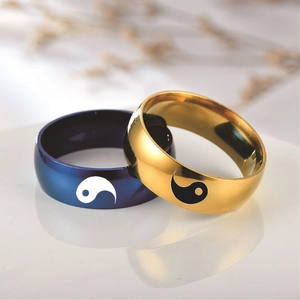 Close-up of blue and gold yin yang rings with a smooth polished finish on reflective surface