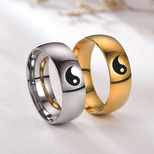 Close-up of gold and silver stainless steel Yin Yang rings with mirror polished finish