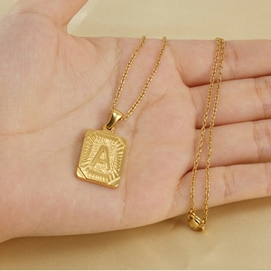 Détail d'un pendentif carré plaqué or 18 carats avec lettre A embossée sur une chaîne fine