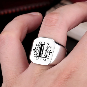 Macro shot of silver signet ring with engraved letter L and vintage vine patterns