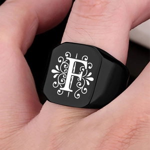 Close-up of black matte stainless steel signet ring featuring engraved white letter F