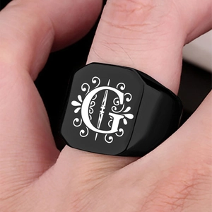 Macro shot of black stainless steel signet ring with engraved letter G and vine patterns