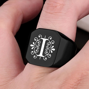 Macro shot of black stainless steel signet ring featuring engraved letter I and vine motifs