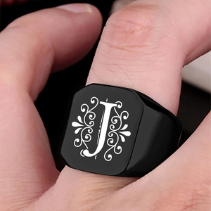 Close-up of black stainless steel signet ring with engraved letter J and floral patterns