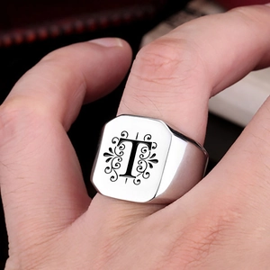Macro detail of stainless steel signet ring with engraved letter T and floral patterns
