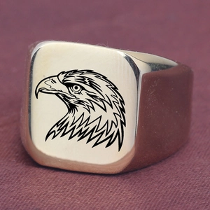 Macro view of polished golden signet ring with black eagle head engraving on purple fabric