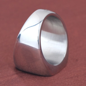 Close-up of industrial style thick silver stainless steel yin yang ring on dark fabric