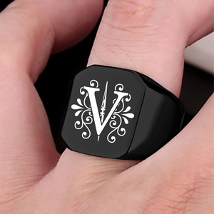 Detail of men's black stainless steel signet ring with engraved V and scrollwork