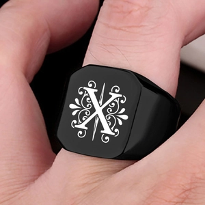Macro shot of men's black stainless steel signet ring with letter X and vintage patterns