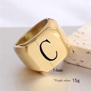 Macro view of a 14mm gold square signet ring with letter C on a stone surface