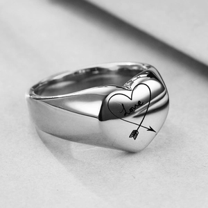Detalle macro de anillo de sello de corazón plateado con grabado Love y flecha