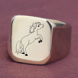 Close-up of a gold stainless steel signet ring featuring a black engraved horse pattern