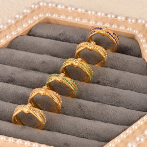 Close-up of set of six gold-plated rings with colorful zircon and crossover design